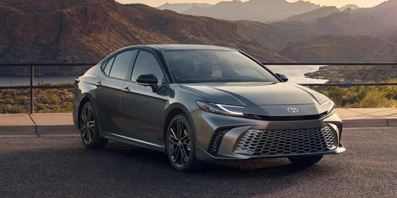 A gray car sitting in the road.