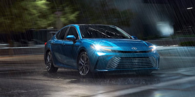 A blue car sitting in the rain.
