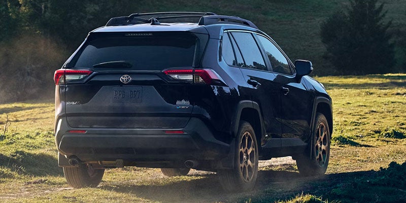 A black suv driving on a dirt road.