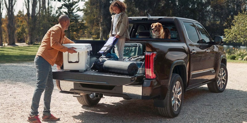 A man getting something out of the bed of a truck.