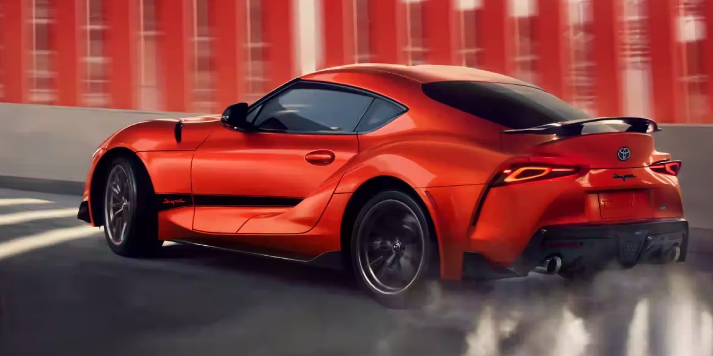 Orange Toyota Supra sports car drifting on a road with smoke behind the tires