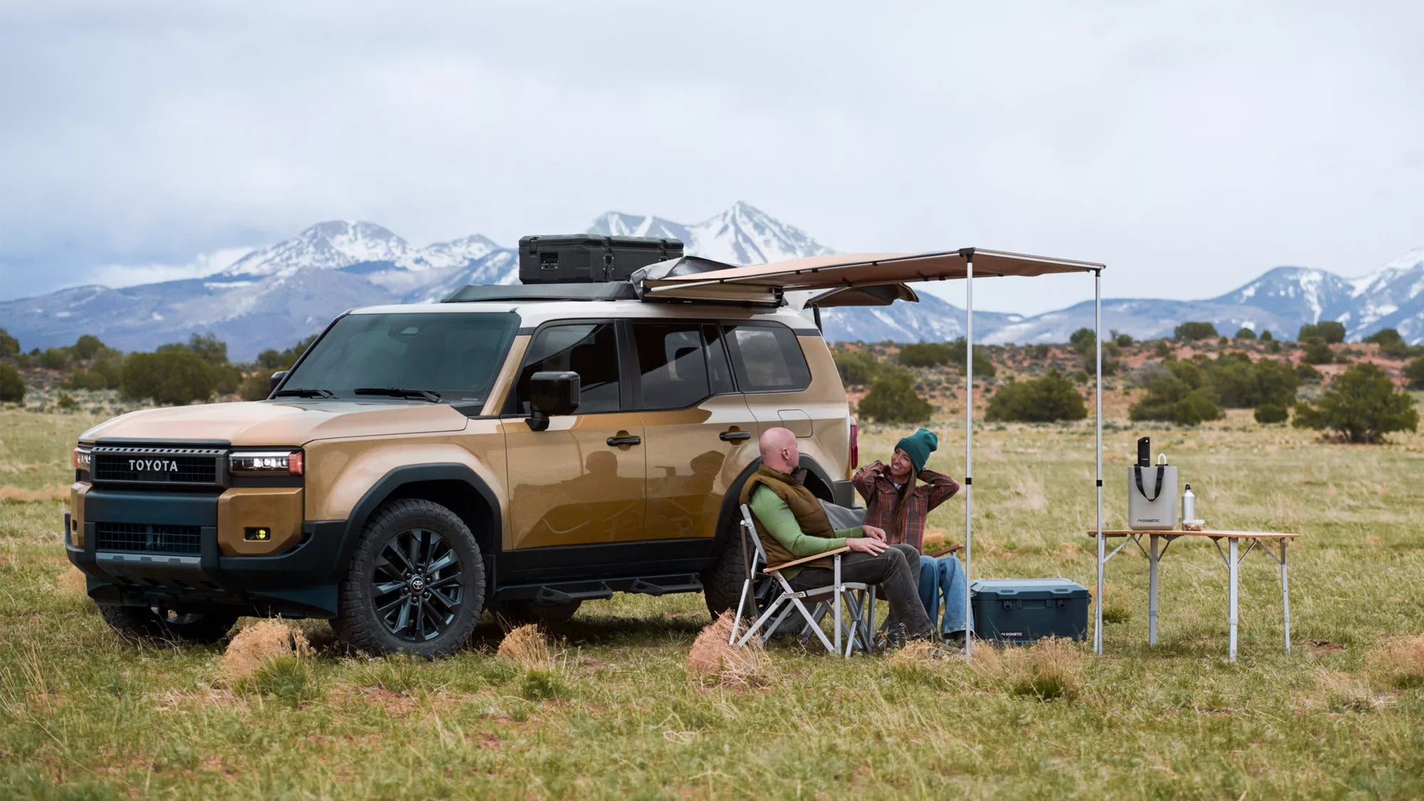 Two people under a tent on a brown suv.
