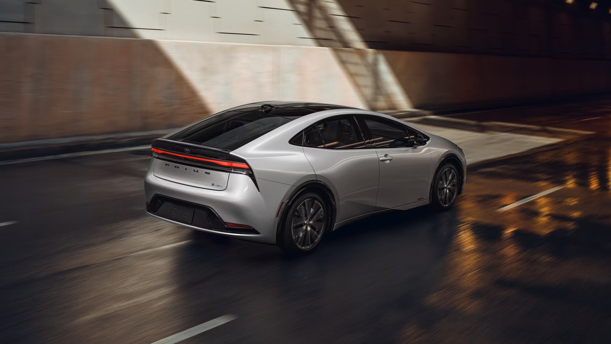 A silver car driving in the street.