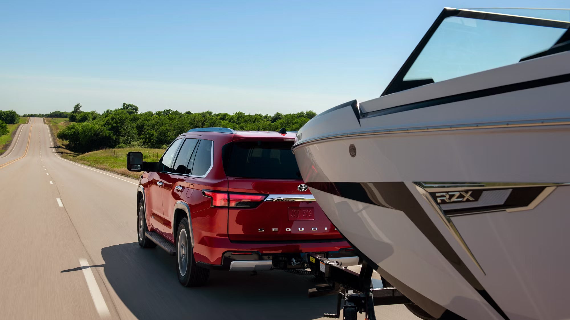 A red suv pulling a boat.