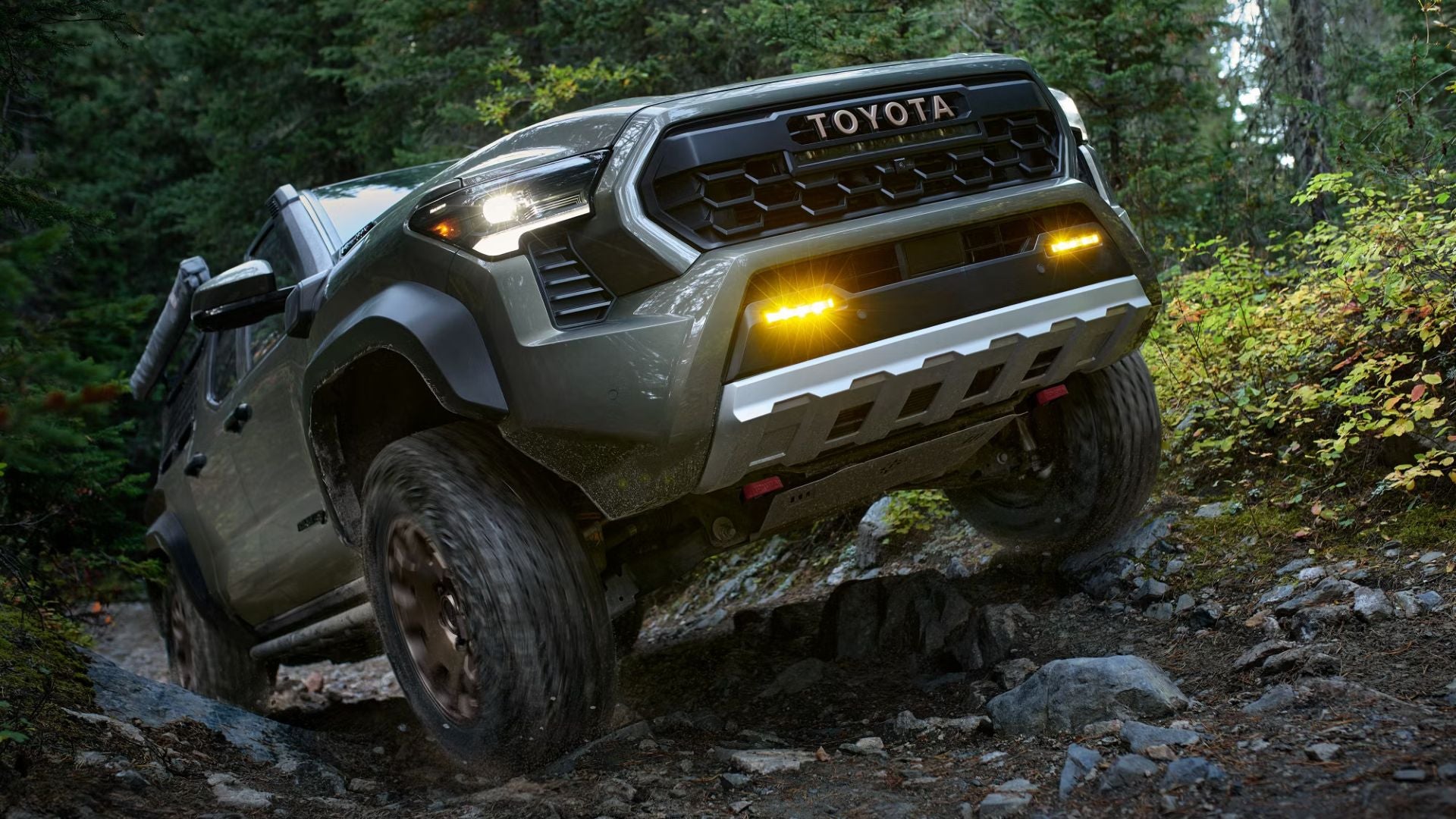 A green truck driving up a hill.