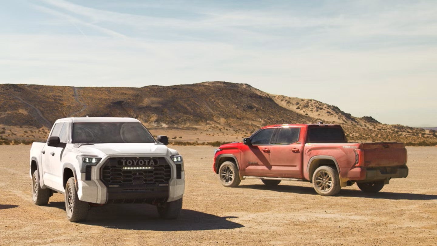 a 2025 tundra gas model and hybrid model parked next to each other in dessert sand