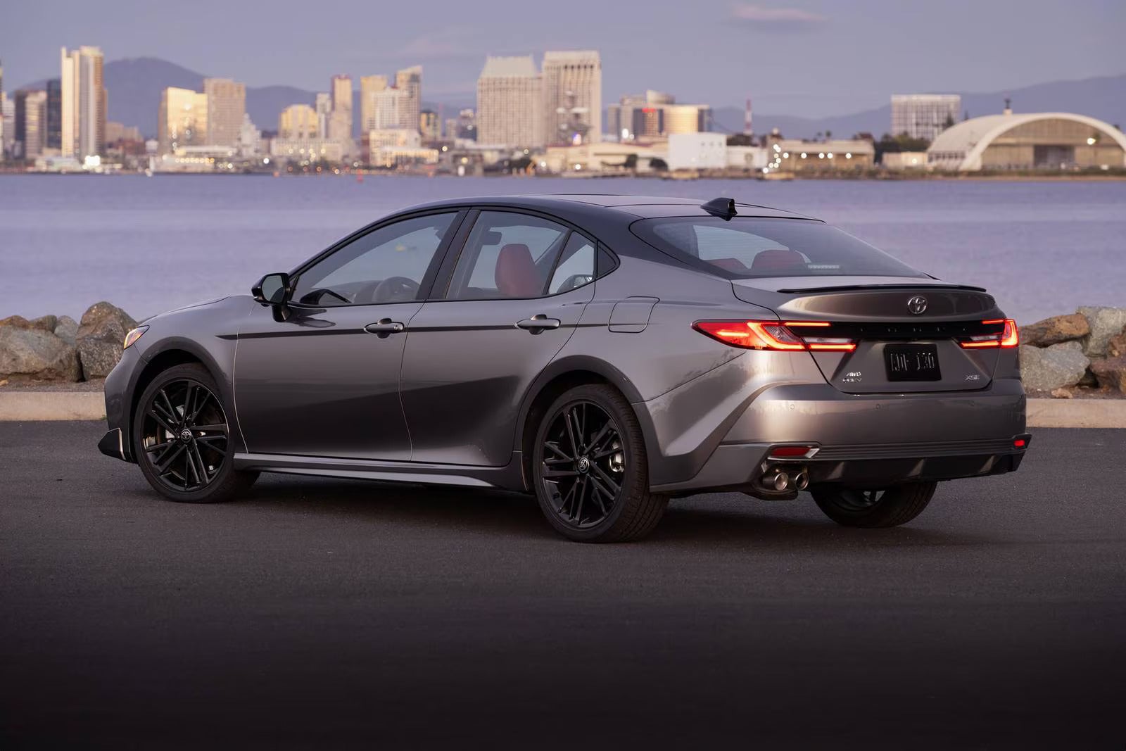 A silver car parked in front of a body of water.