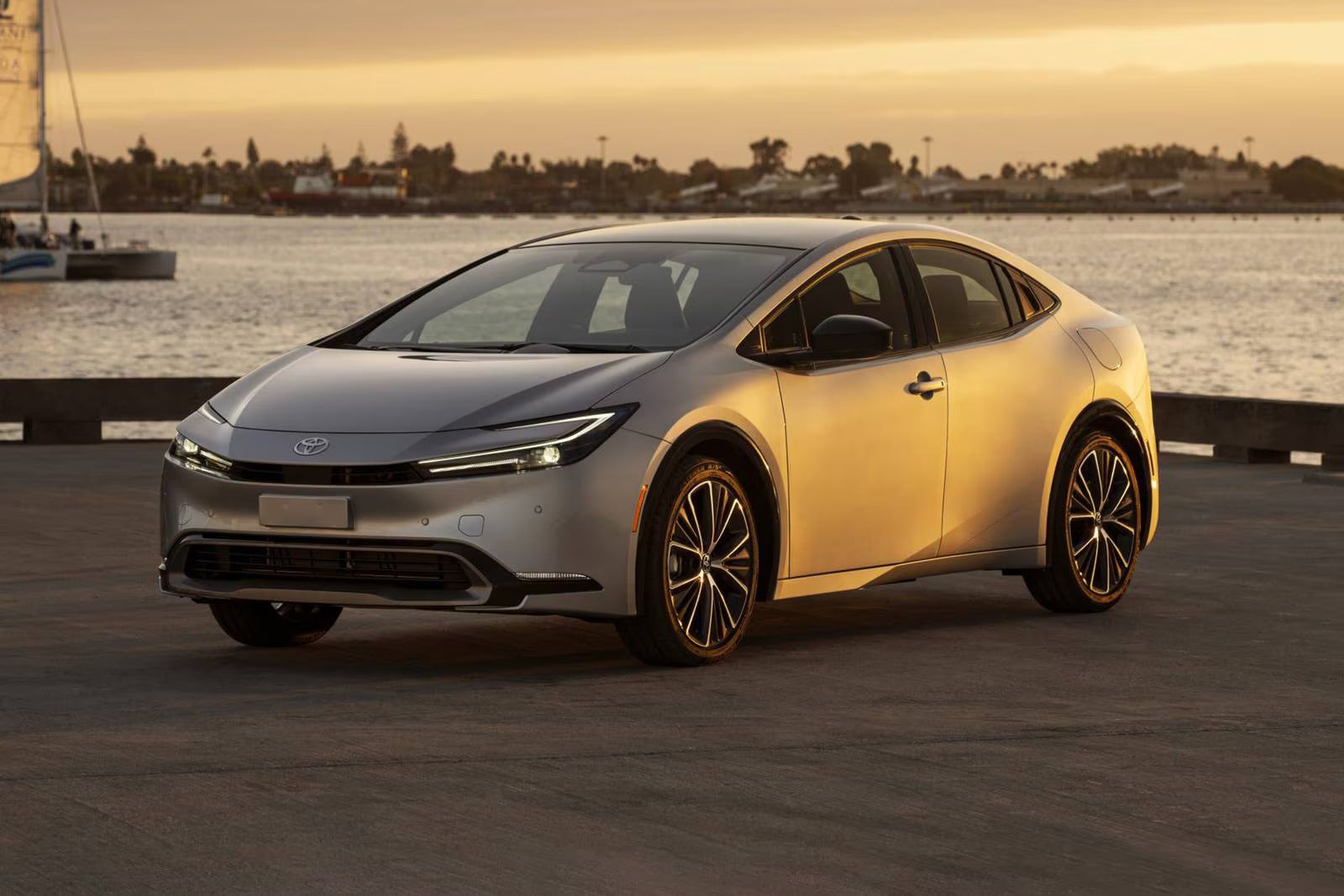A silver car parked in front of water.