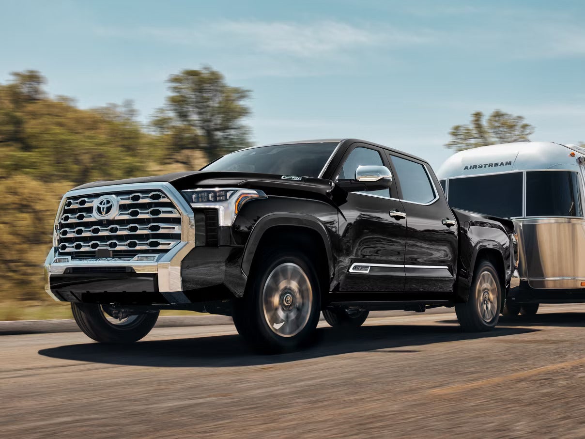 A black truck pulling a trailer on the road.