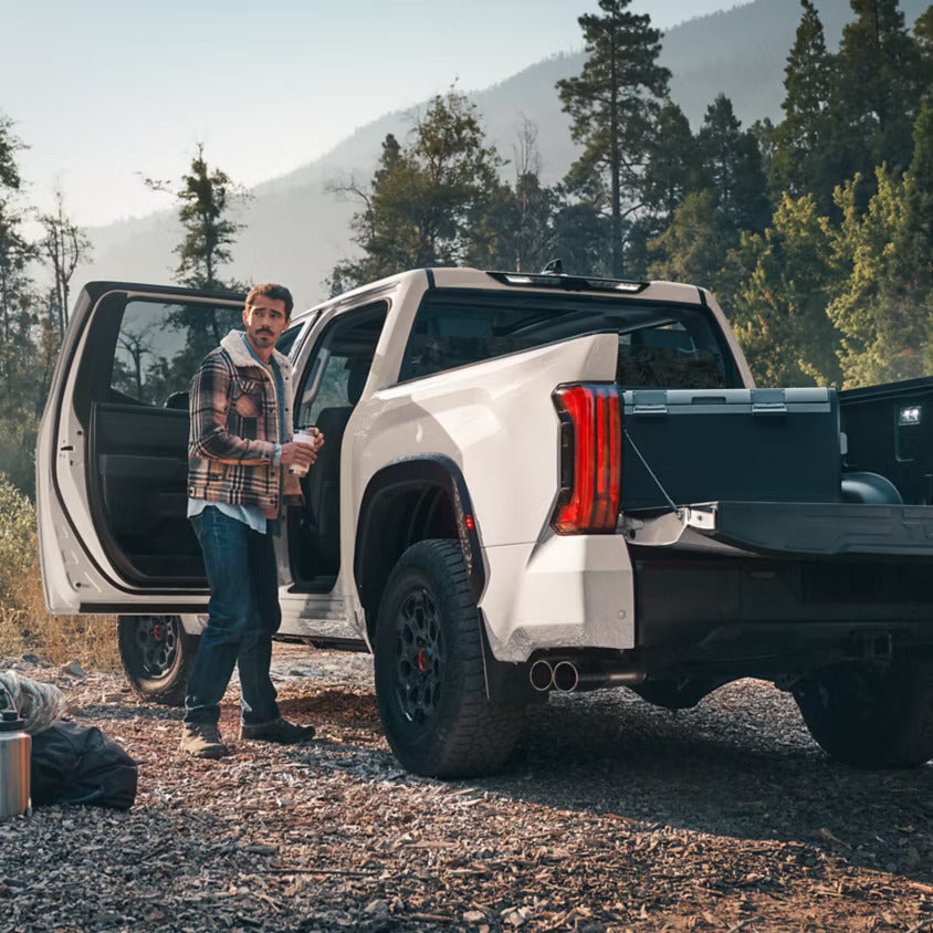 A man getting into the back of a white truck.