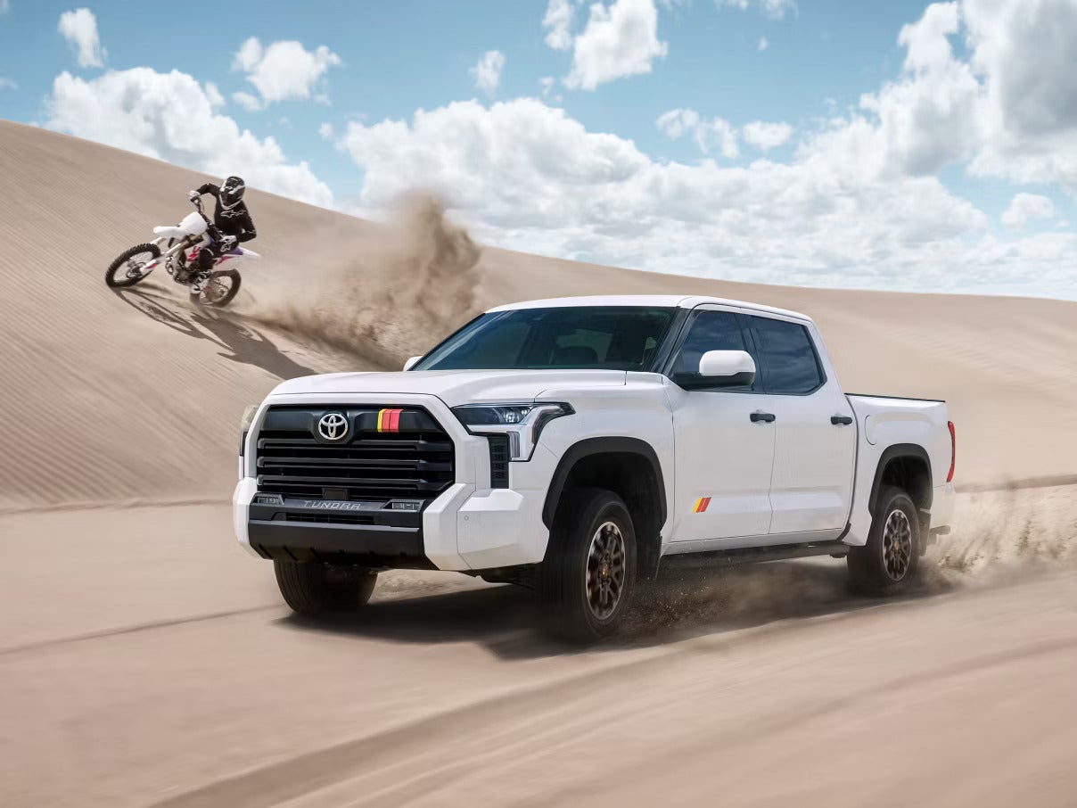 A white truck and dirt bike driving off-road.
