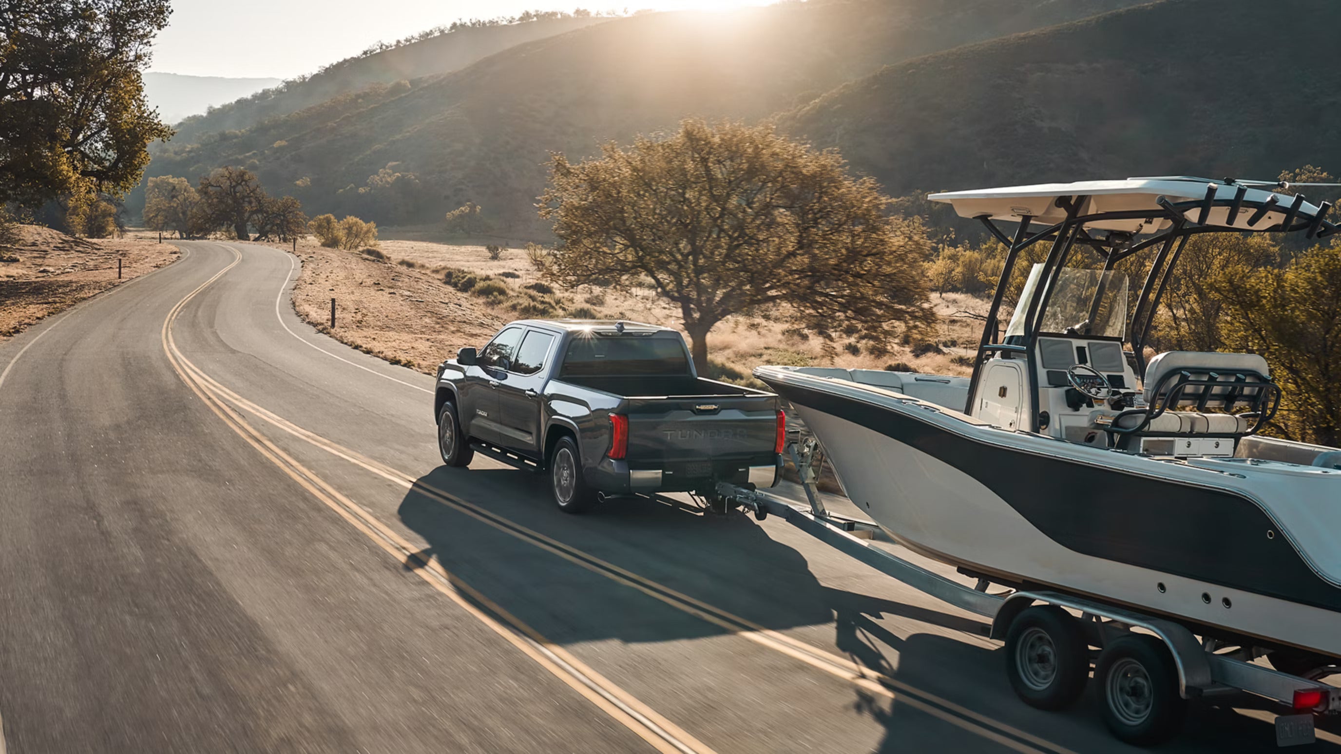 A silver truck pulling a trailer.